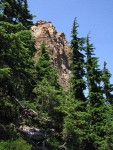 Mountain Hemlocks frame serpentine cliff at east end of Twin Sisters Range above Elbow Lake